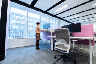 Ergonomische werkplek met zit-sta bureau, ergonomische bureaustoel en roze akoestische wand
